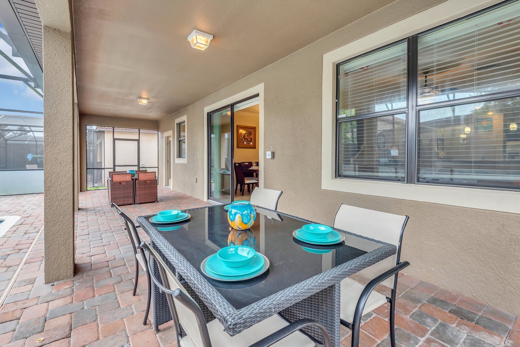 An outdoor patio with a glass-top table, wicker chairs, and blue plates.