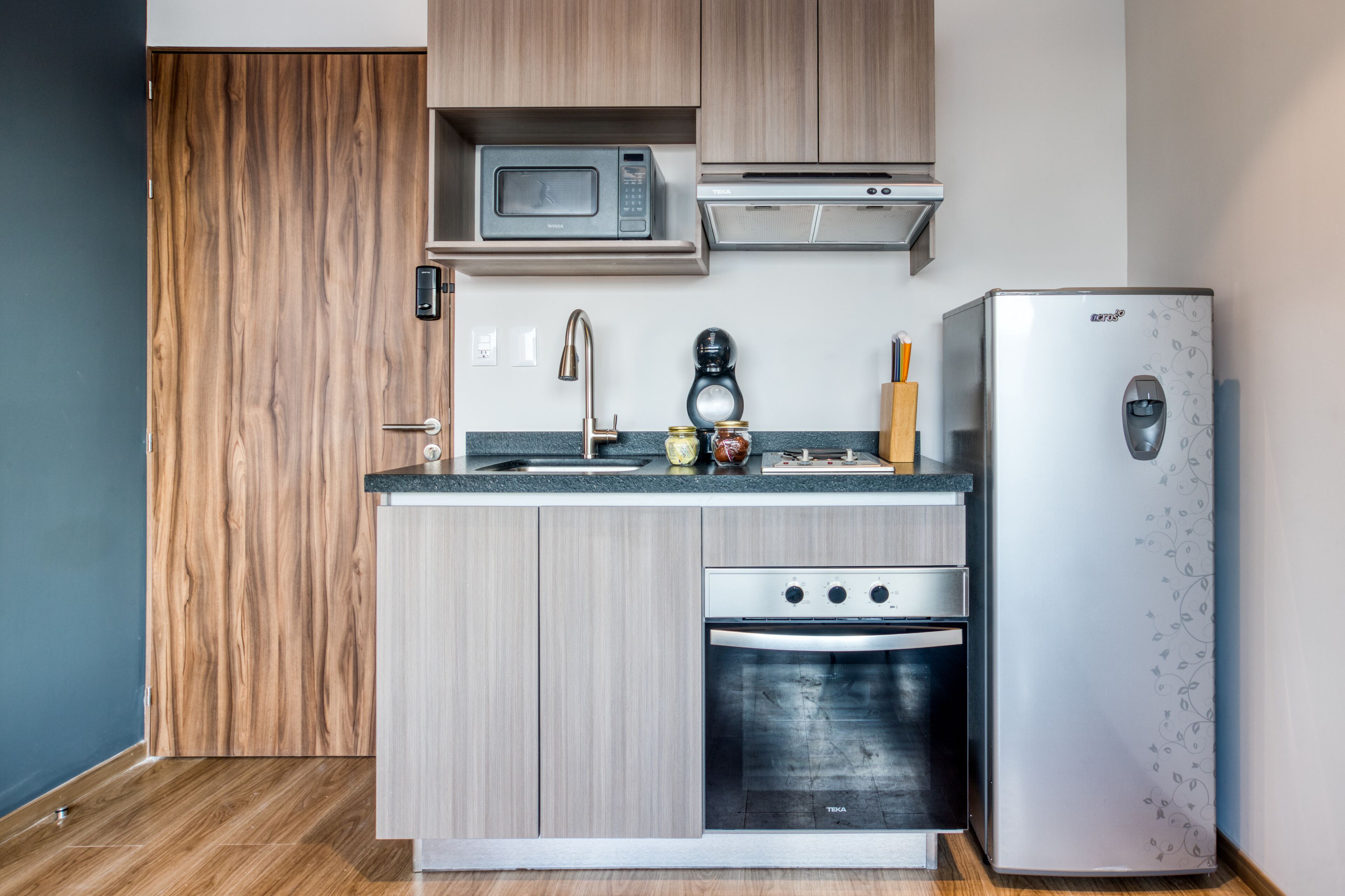 A compact kitchen with a microwave, coffee maker, and refrigerator.