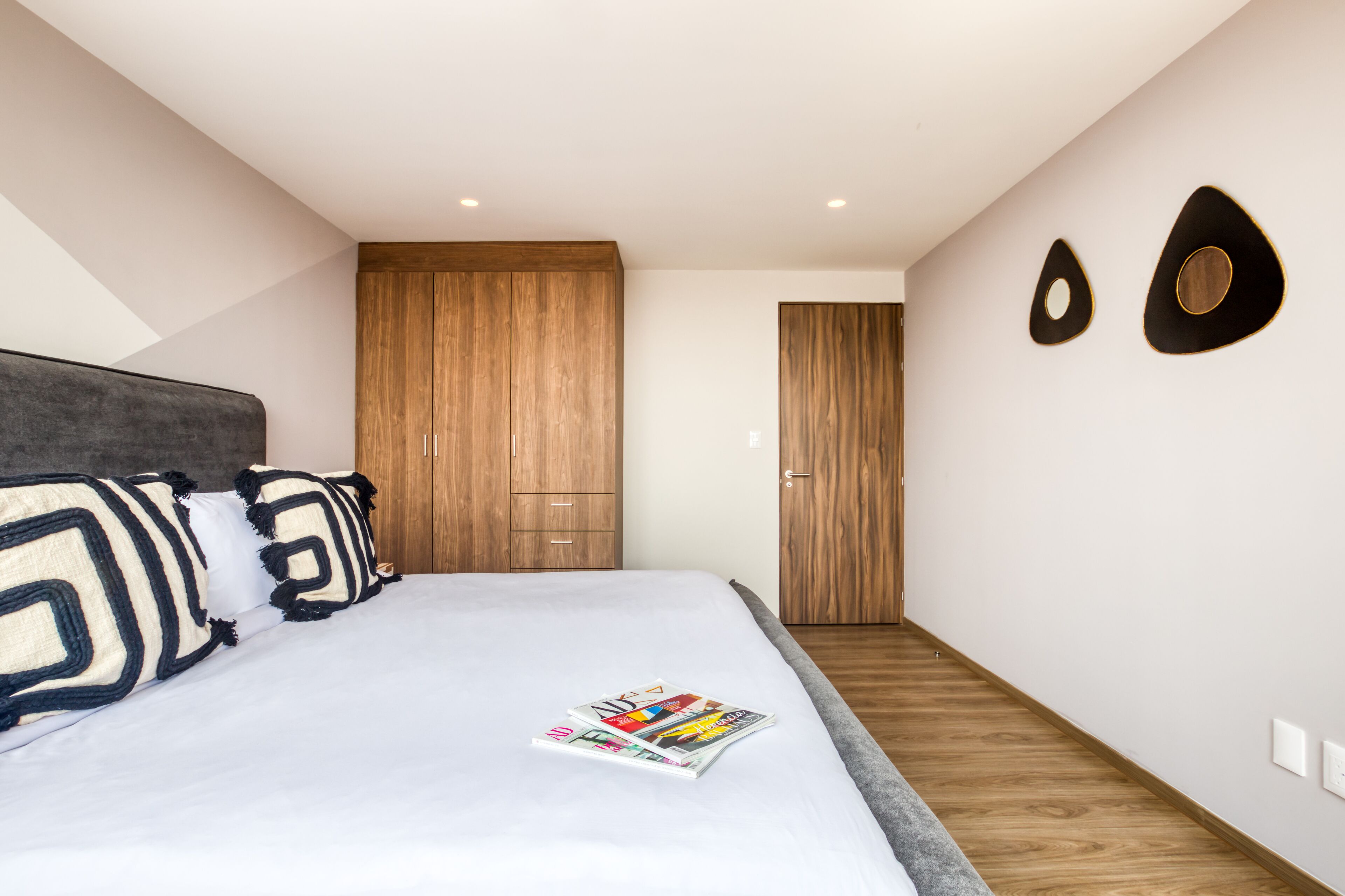 Ein modernes Schlafzimmer mit einem großen Bett, einem Holzschrank und einer Zeitschrift auf dem Bett.