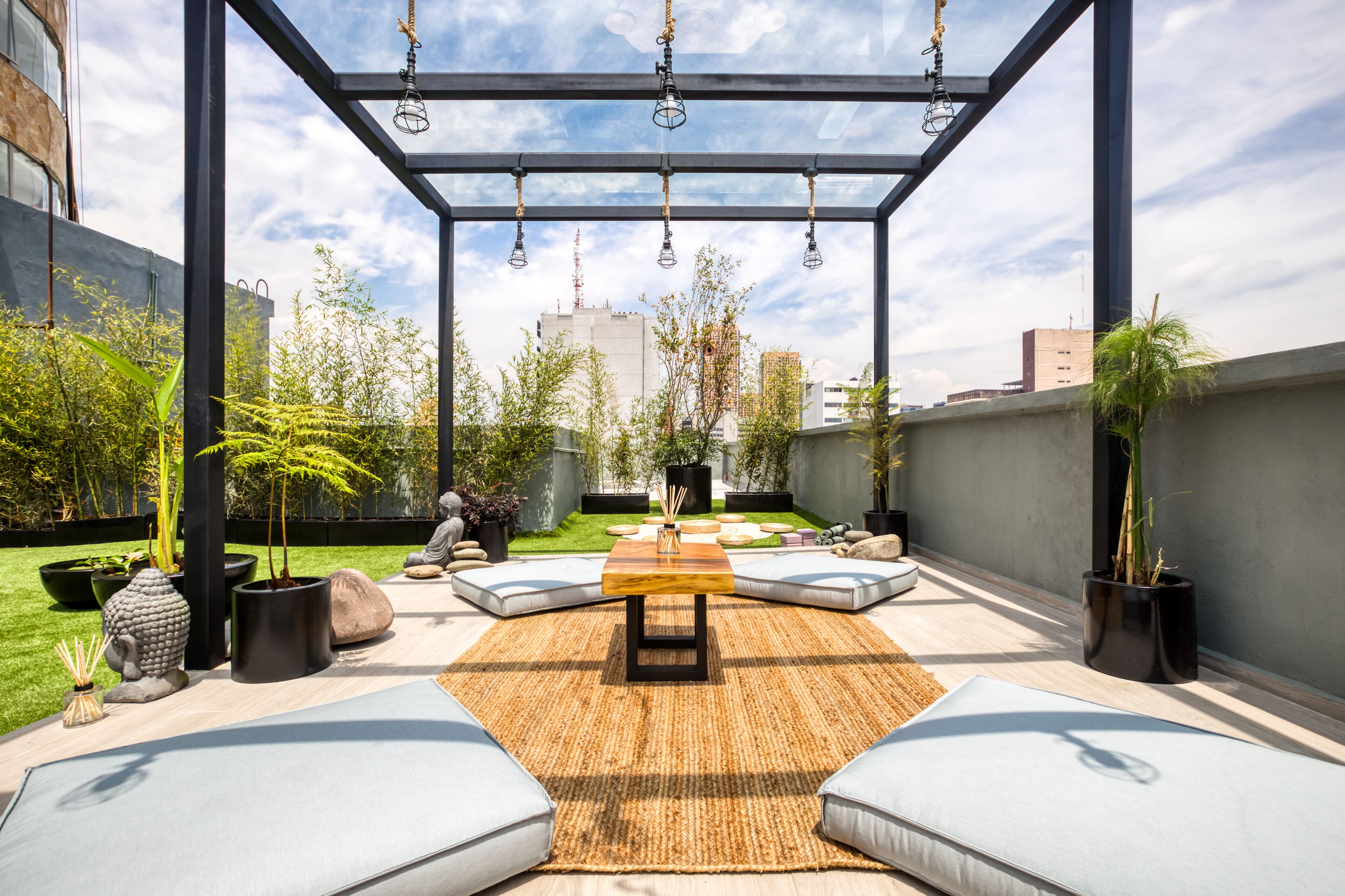 A rooftop patio with a central table, seating, and potted plants.