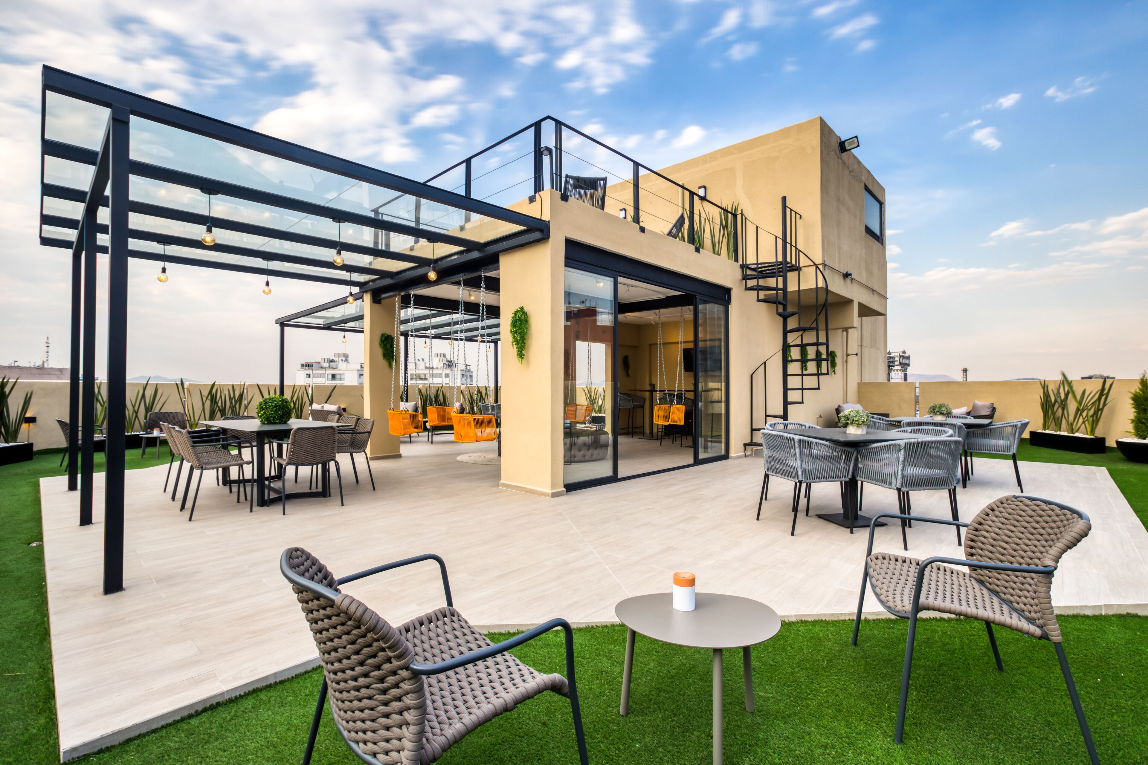 An outdoor patio area with modern furniture, a glass-enclosed space, and a view of the cityscape.