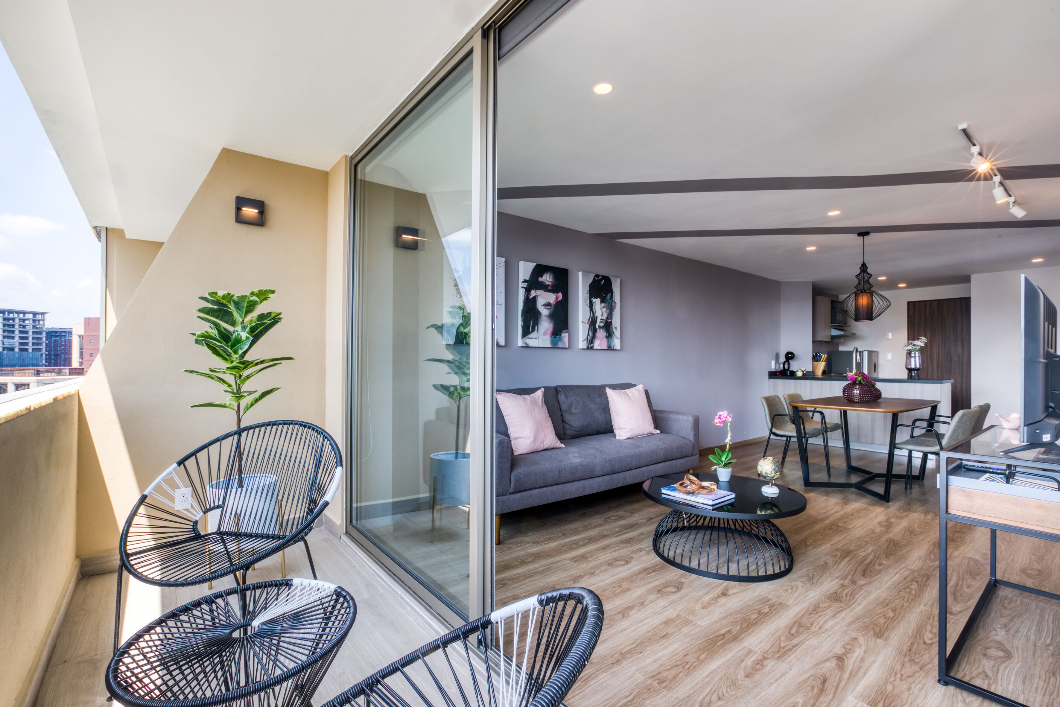 A modern apartment with a balcony, a sofa, a dining area, and a kitchen.