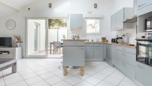 Een moderne keuken met een centraal eiland, inbouwapparatuur en een eethoek met uitzicht.