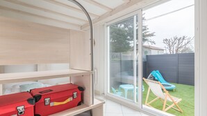 Een kamer met een schuifdeur naar een achtertuin met een glijbaan en een klein tafeltje.