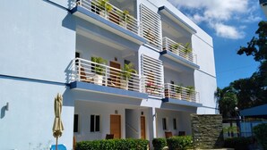 A modern multi-story building with balconies, a swimming pool, and outdoor seating.