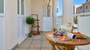 A balcony with a wooden table, a potted plant, a wine glass, and a croissant. - Hedera Estate, Hedera A38 (Dubrovnik)