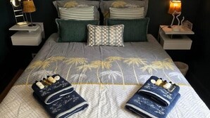 A neatly made bed with a patterned bedspread, two towels, and multiple pillows.