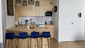 A modern kitchen with a central island, bar stools, and a white door.