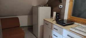 Une cuisine compacte équipée d’un réfrigérateur, d’une machine à café et d’un four à micro-ondes, le tout installé sur un plan de travail.