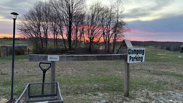 Een parkeersbord voor Glamping Park, met een metalen bank en een lantaarnpaal op de voorgrond.
