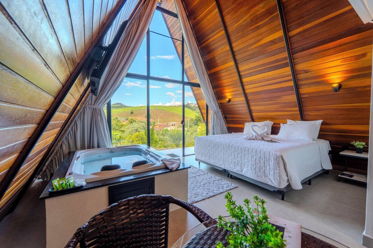 Un dormitorio con cama, bañera de hidromasaje y vistas al campo.