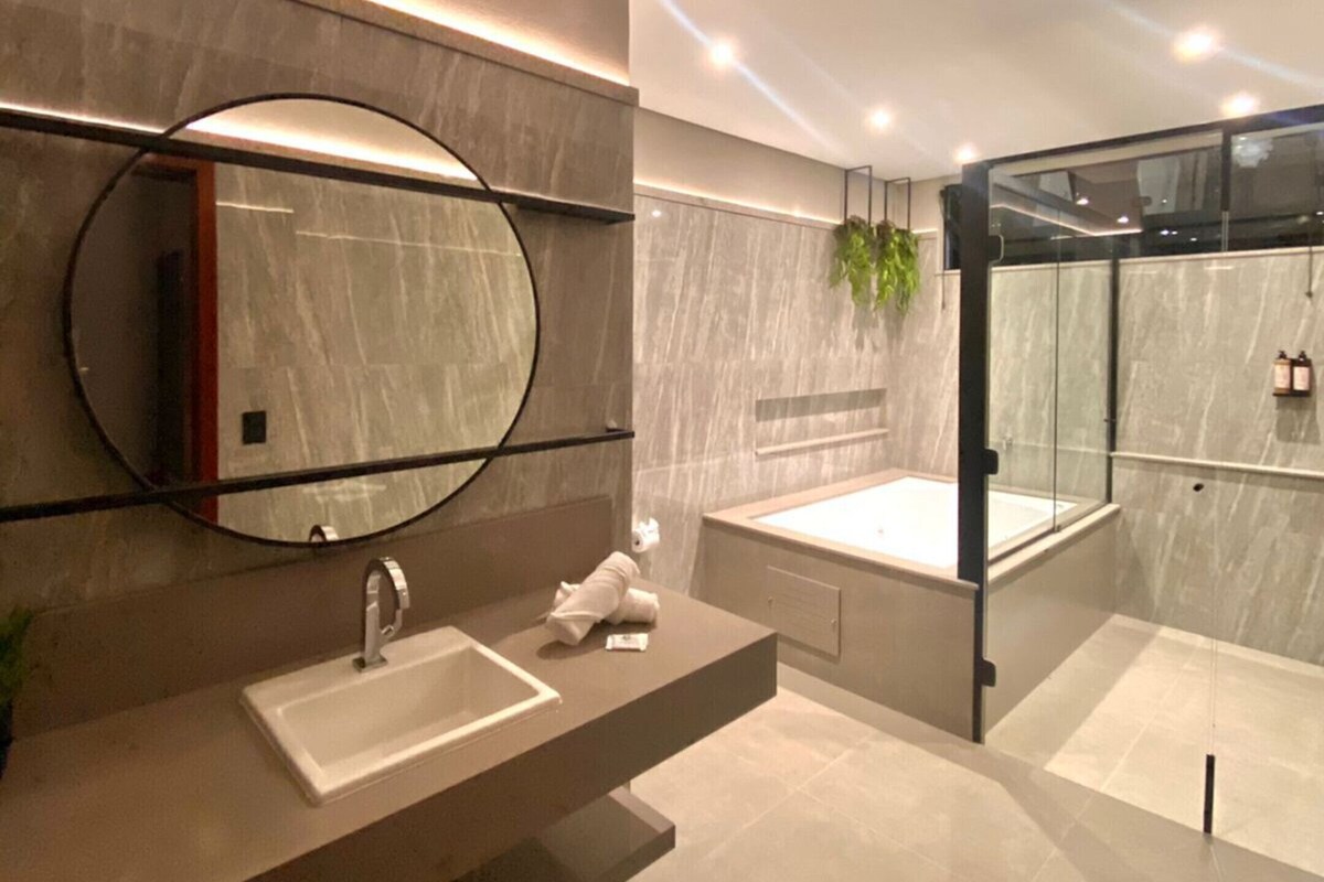 A modern bathroom with a large mirror, a sink, a bathtub, and a glass-enclosed shower.