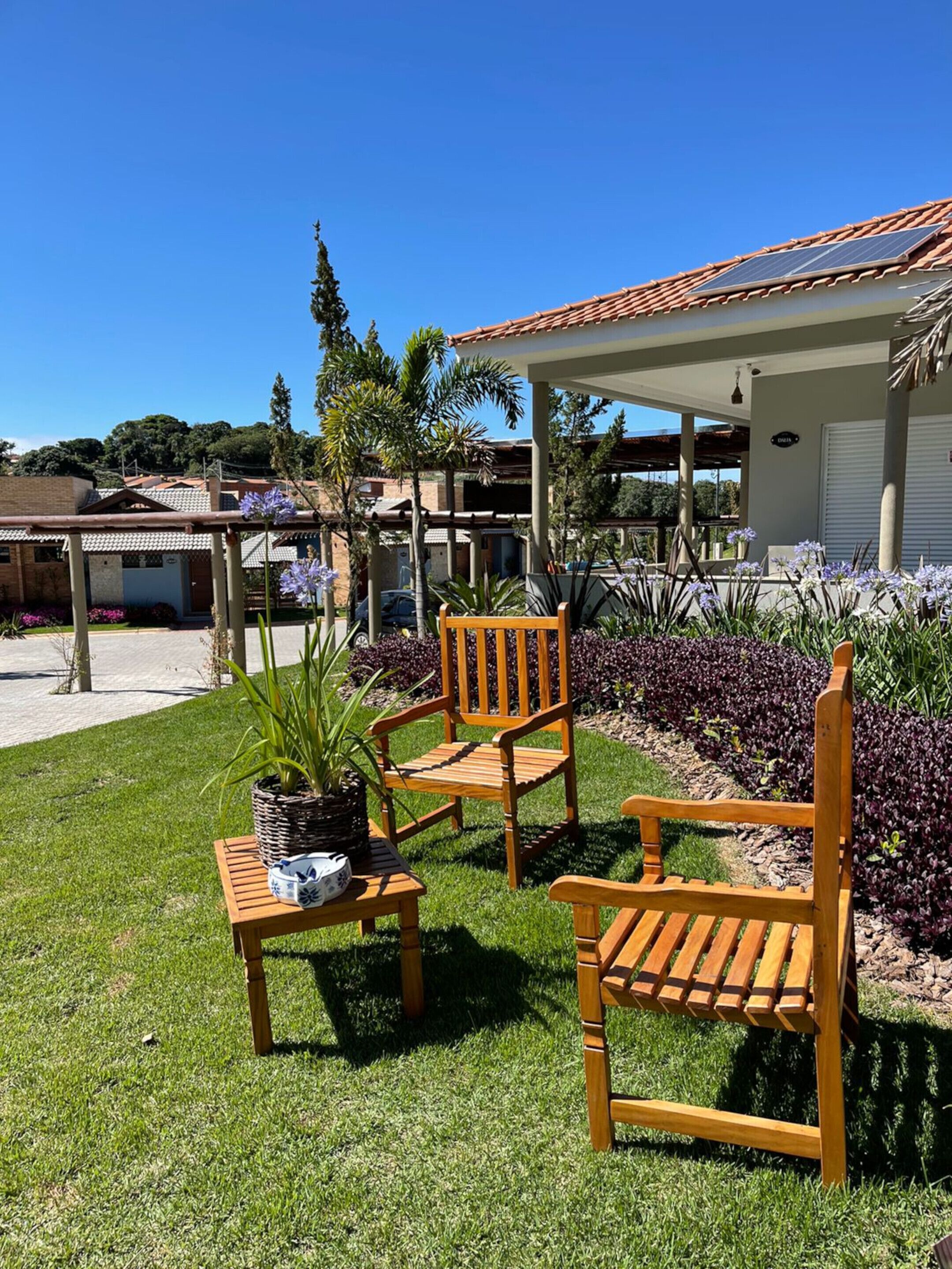 A patio area with two wooden chairs, a small table, and a potted plant.