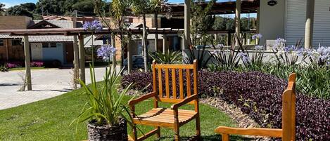 A patio area with two wooden chairs, a small table, and a potted plant.