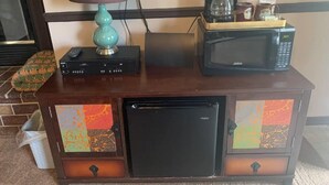 Een houten kast met een televisie, koffiezetapparaat en magnetron.