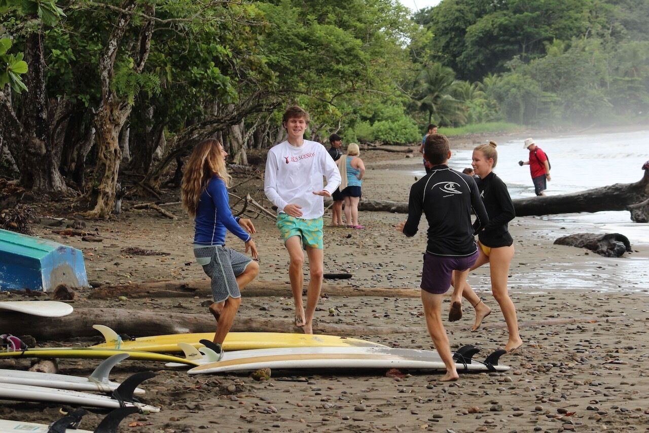 Une plage où l’on voit des gens se promener et des planches de surf alignées.