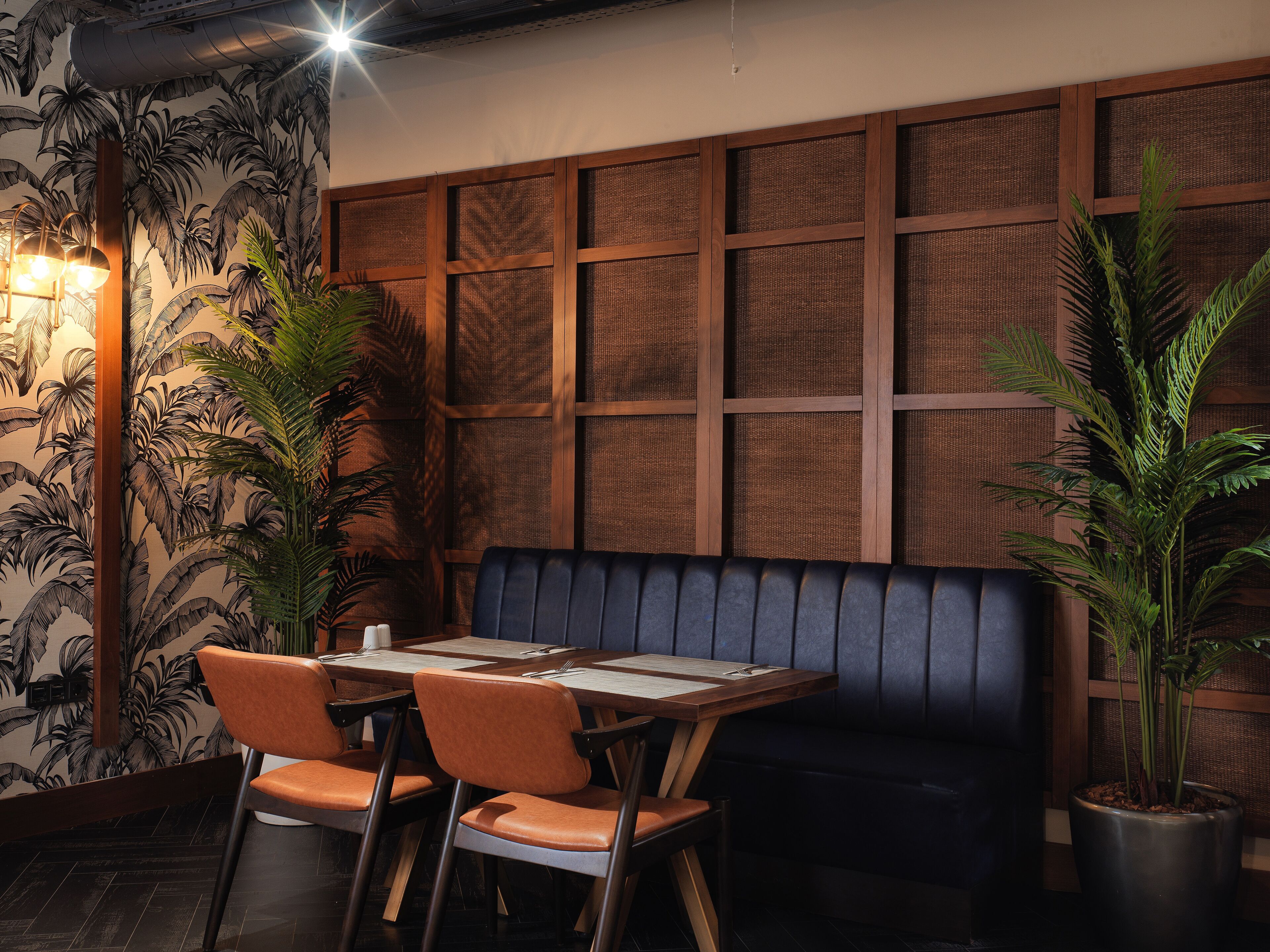 A restaurant with a wooden table, orange chairs, and a dark blue bench.