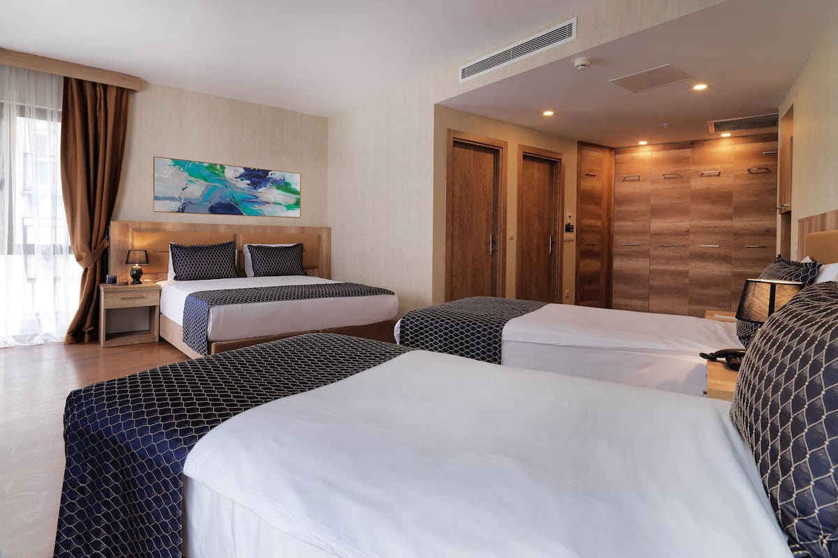 A hotel room with two beds, a nightstand, a desk, a painting, and a wardrobe.