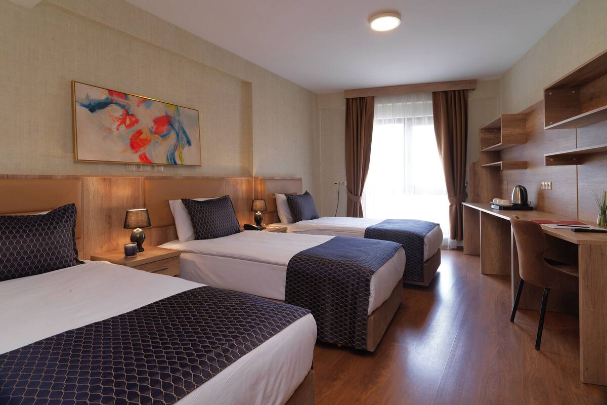 A hotel room with two beds, a desk, and a chair.