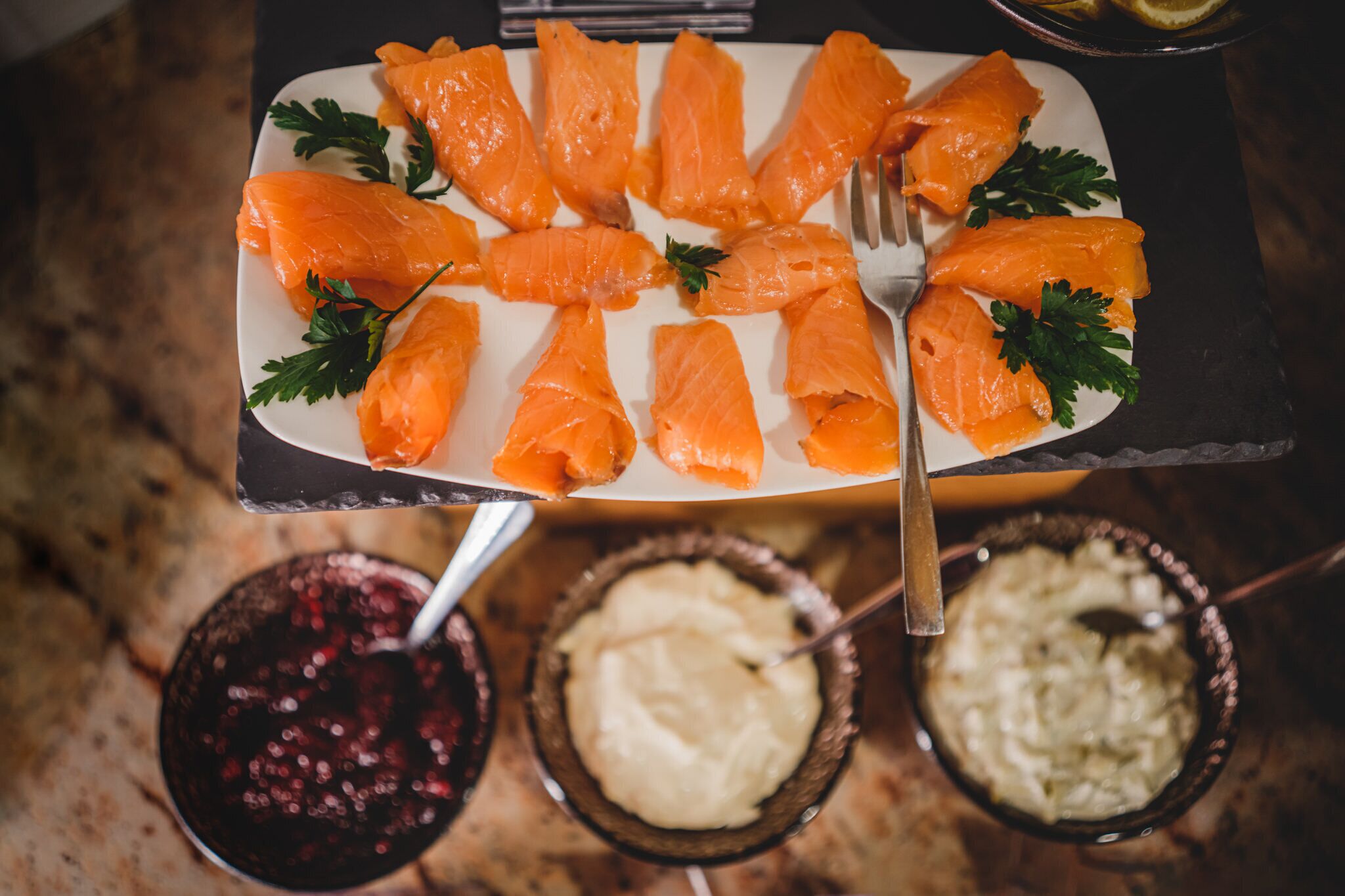 Um prato de salmão defumado com acompanhamentos, acompanhado por duas tigelas de pratos de acompanhamento.