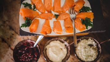 Um prato de salmão defumado com acompanhamentos, acompanhado por duas tigelas de pratos de acompanhamento.