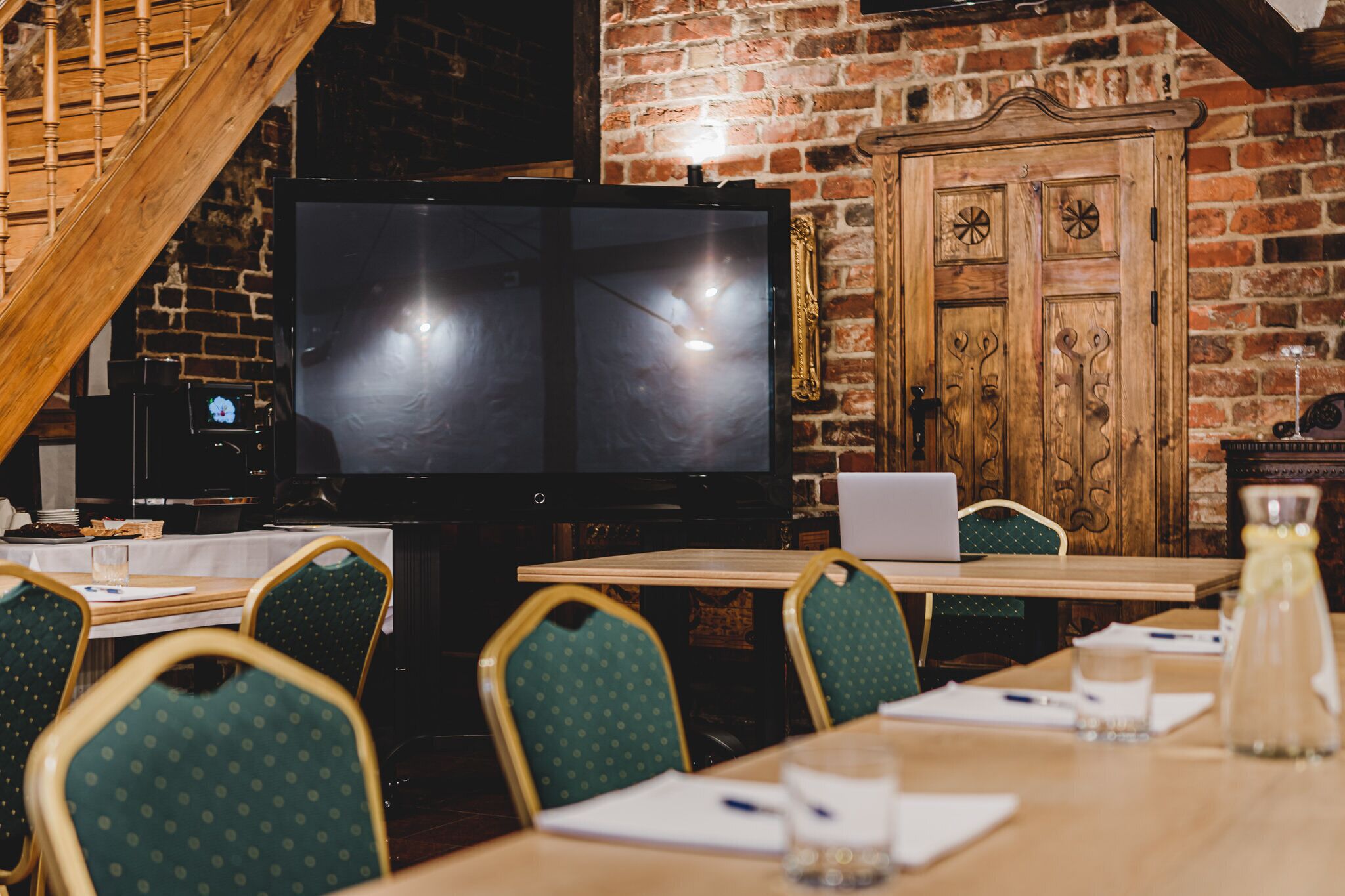 A restaurant with brick walls, wooden furniture, and a large flat-screen TV.