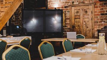 A restaurant with brick walls, wooden furniture, and a large flat-screen TV.