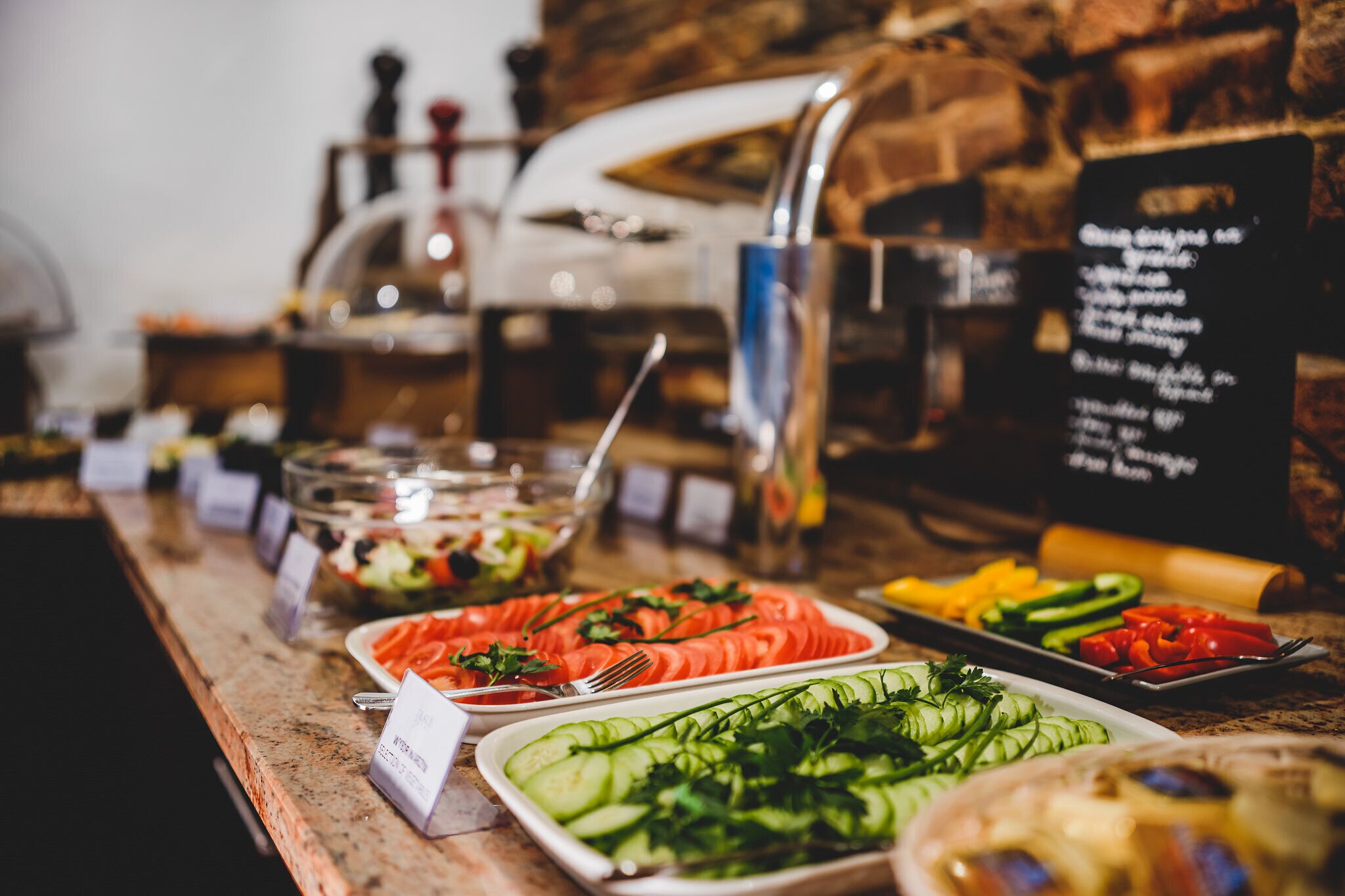 Un bufé con diferentes opciones de comida y un panel con el menú.