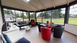 Una sala de estar moderna con una mesa de centro de vidrio, un pouf rojo y un sofá.