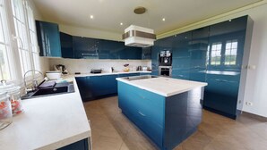 Una cocina moderna con armarios azules, una isla central y un horno empotrado.