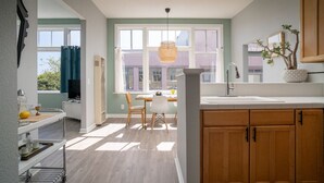 Una cocina moderna con armarios de madera, una encimera blanca y una zona de comedor con una mesa y sillas.