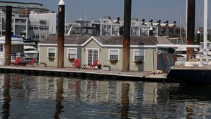 A waterfront property with a dock, a small building with a sloped roof, and a row of red chairs along the dock.