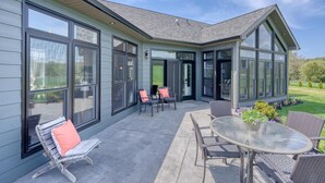 Una casa moderna con ventanas amplias, un patio con mobiliario exterior y un césped bien cuidado.