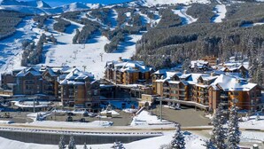Une station de montagne enneigée, dotée d'un télésiège, de bâtiments d'hébergement et d'un parking.