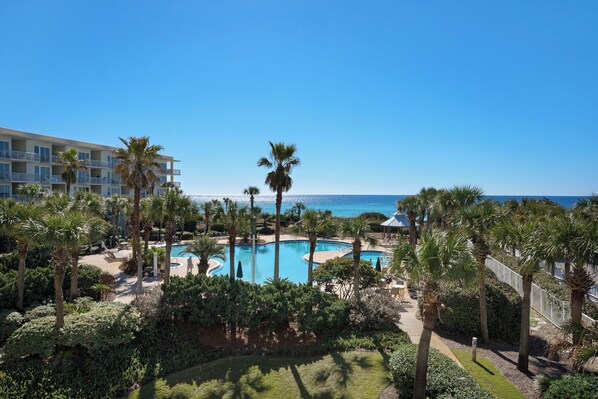 Relax by the resort's large pool surrounded by lush greenery and palm trees.