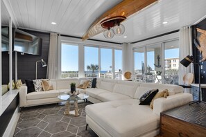 Uma sala de estar moderna com um sofá modular, uma mesa de centro de vidro e vista para o mar.