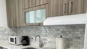 Eine moderne Küche mit Holzausstattung, einer Mikrowelle, einer Kaffeemaschine, einem Spülbecken und einem Geschirrständer.