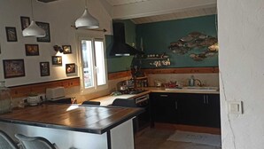 Una cocina con encimera de madera, un lavamanos y una estufa. Hay cuadros en la pared y una ventana con vistas al exterior.