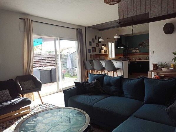 A living room with a sofa, chairs, a glass coffee table, and a sliding glass door leading to a patio.