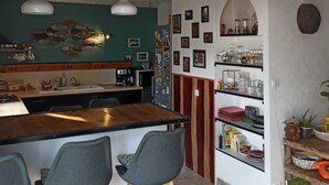 Una cocina con isla central, taburetes de bar, un refrigerador y diversos electrodomésticos.
