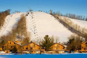 Une station de ski dotée d'un télésiège, de chalets en bois et offrant un paysage enneigé.
