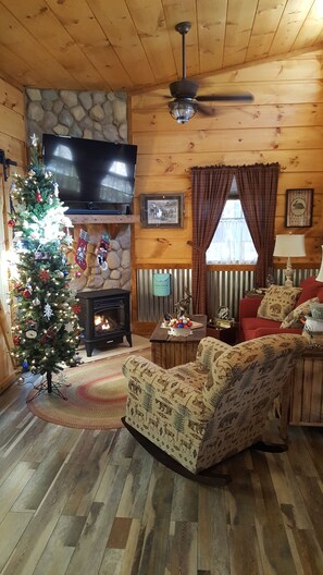 Cozy living room with a stone fireplace, television, and comfortable seating.