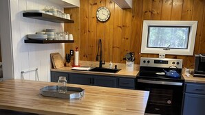 Eine moderne Küche mit Holzwänden, einem eingebauten Backofen, einem Spülbecken und einer Wanduhr.