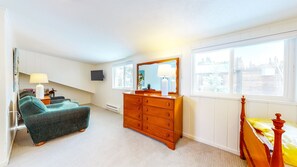 Cozy retreat with a large bed, dresser, and seating area.
