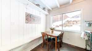 Enjoy meals in this dining area with a wooden table and chairs, a painting on the wall, and a window offering a view.
