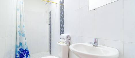 Un baño con inodoro, lavabo, cortina de ducha y paredes de azulejos.