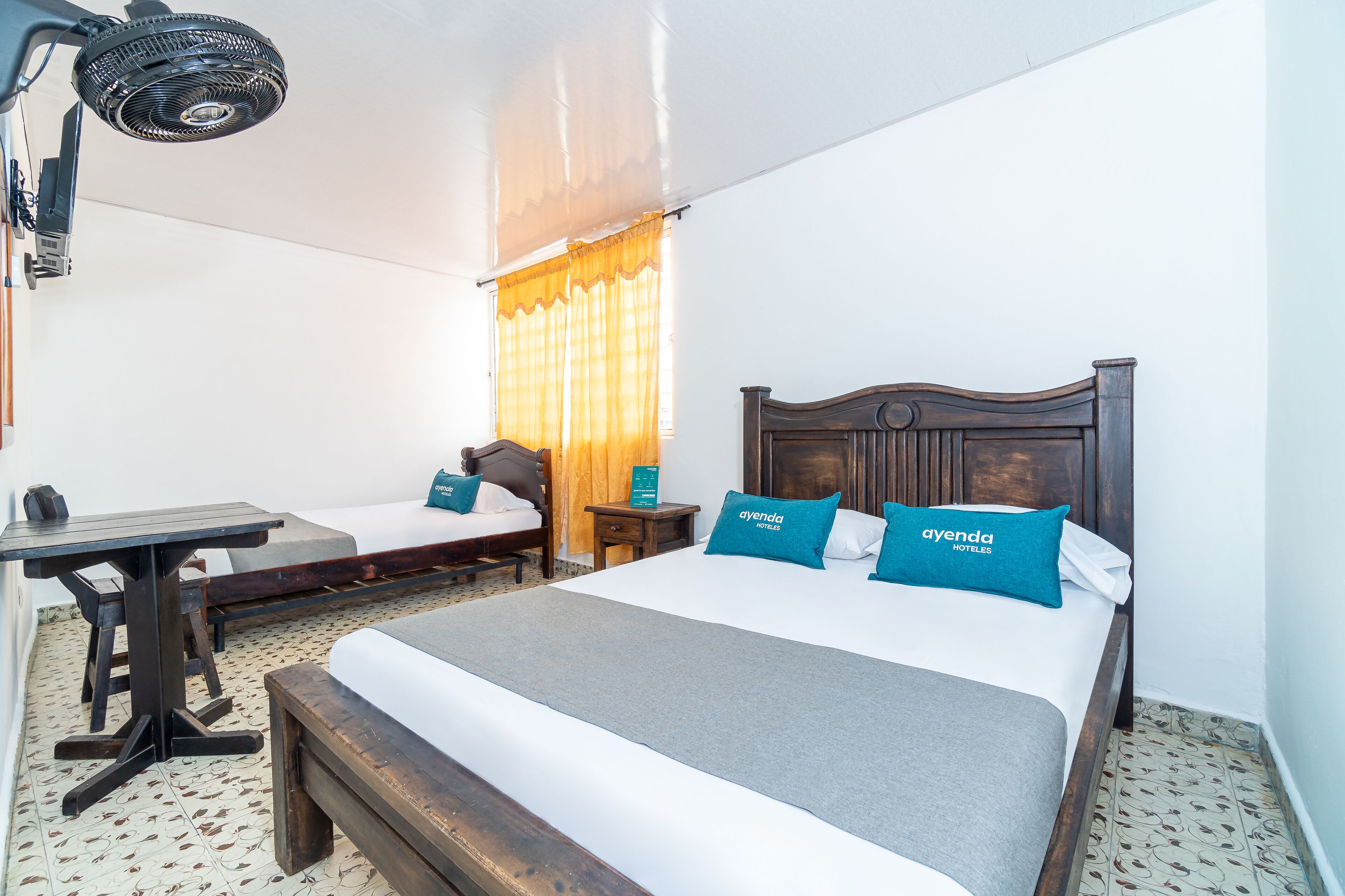 A hotel room with a large bed, a smaller bed, a desk, and a chair.