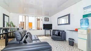 Una sala de estar moderna con un sofá, un televisor y un dispensador de agua.