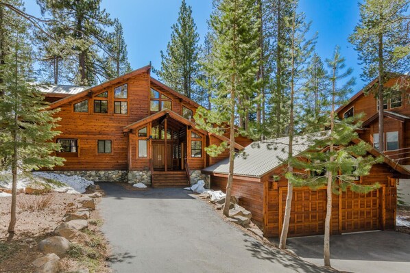 A log cabin with a stone foundation, large windows, and a covered porch.