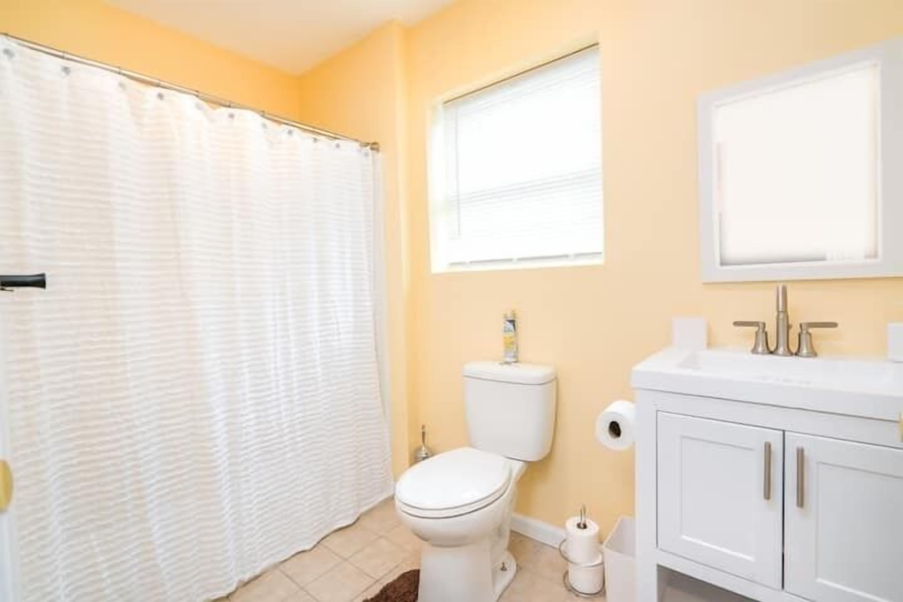 A bathroom with a white toilet, a white sink, and a shower curtain.
